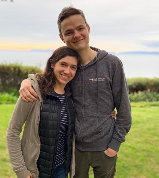 Caleb Stanford with his wife Ariana standing on green grass near a coastline
